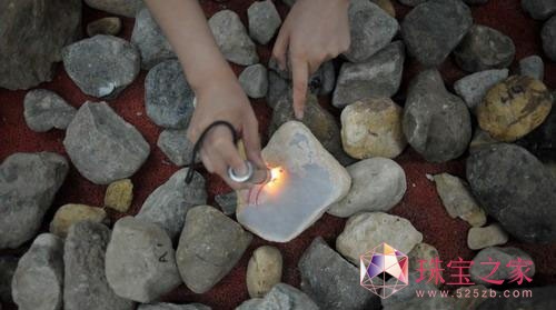一塊翡翠原石在強光手電照射下晶瑩剔透，然而，誰都不敢保證它內部的成色究竟如何本組圖片記者劉陽攝